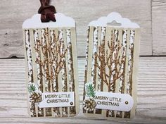 two tags with christmas trees on them are hanging from strings, and the tag says merry little christmas