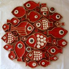 a red and white plate with fish on it's side, in the shape of a circle