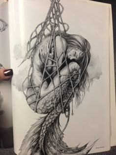 an open book with a drawing of a woman holding a fish in it's mouth