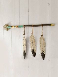 three feathers hanging on a wall with an arrow