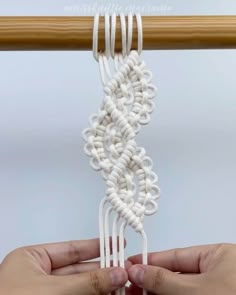 two hands are working on an object with white yarn