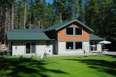 a house with a green roof and trees in the background