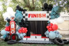 an arch made out of tires and balloons is displayed in front of a finish sign