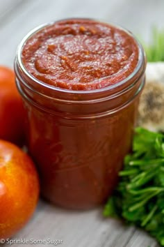 a jar of tomato sauce next to tomatoes and parsley