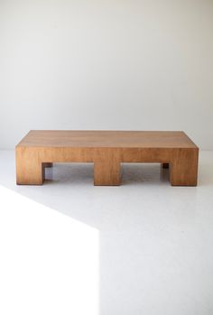 a wooden coffee table sitting on top of a white floor in front of a wall