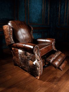 a brown leather chair and foot stool in a room with blue walls, wooden floors and wood flooring