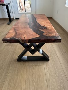 a wooden table sitting on top of a hard wood floor next to a window in a living room