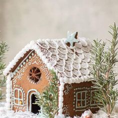 a small gingerbread house is decorated with icing and pine branches for the holiday season