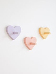 three heart shaped magnets on a white wall with one pointing at the other side