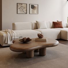 a living room with white couches and a wooden table in front of a large window