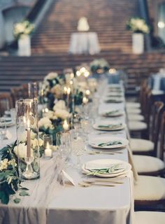 a long table is set with white flowers and greenery for an elegant wedding reception