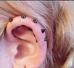 a close up of a person's ear with small black spikes on the side