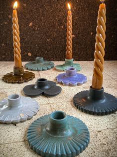 several candles sitting on top of a tile floor next to plates and saucer holders