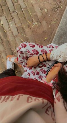 two people laying on the ground with one holding a cell phone and another looking at it