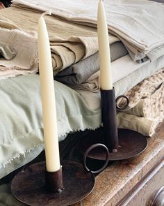 two candles sitting on top of a table next to blankets