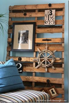 a bed made out of wooden pallets with pictures on the wall above it and a blue pillow