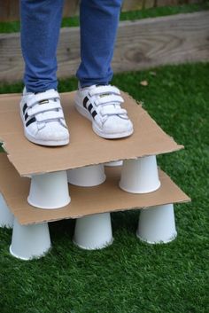 a person standing on top of a cardboard box with white shoes on it and the words stand on paper cups without breaking them