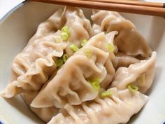 a white bowl filled with dumplings and chopsticks