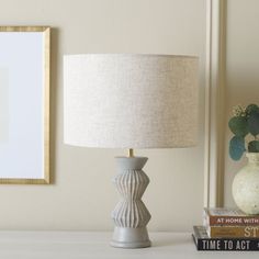 a white table with a lamp and some books on it next to a framed photograph