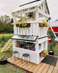 an outdoor kitchen made out of pallet boards and wooden planks with potted plants on the roof