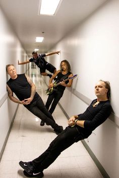 a group of people standing in a hallway with guitars on their feet and one man holding an electric guitar