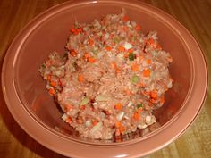 a pink bowl filled with food on top of a wooden table