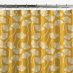 a yellow shower curtain with white leaves on it and a metal bar in the background