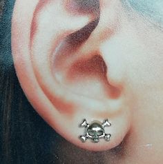 a woman's ear with two skull and crossbones attached to the side