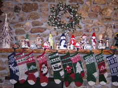 christmas stockings hanging on a mantle in front of a stone wall