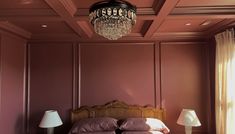 a bedroom with a chandelier hanging from the ceiling and two lamps on either side of the bed