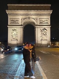 two people are standing in front of the arc de trioe at night, with their arms around each other