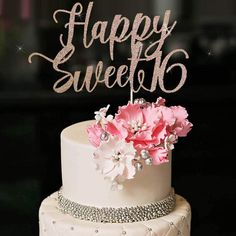 a white cake topped with pink flowers and the words happy sweet 16 on it's top