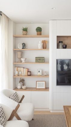 a living room filled with furniture and a flat screen tv on top of a wooden shelf