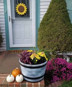 a potted planter with flowers and pumpkins in front of a house