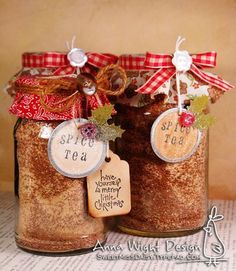 two jars filled with spices and tags on top of a table next to each other