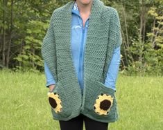 a woman wearing a green crocheted cardigan with sunflowers on it