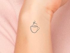 a woman's arm with a small tattoo of a coffee cup on the wrist