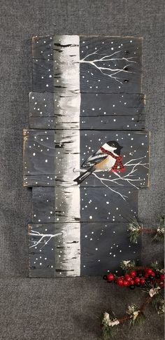 a bird sitting on top of a tree branch in front of snow covered trees and berries