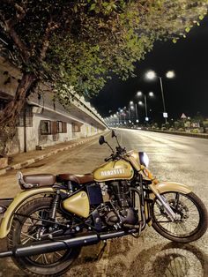 a motorcycle is parked on the side of the road near a tree and street lights