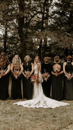 a group of women standing next to each other wearing black dresses and holding bouquets