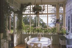 a dining room table with chairs and potted plants in the window sill area