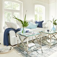 a living room filled with white furniture and lots of windows