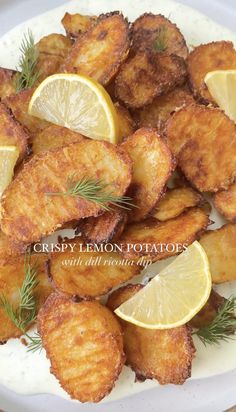 fried lemon potatoes on a white plate topped with fresh rosemary garnish and sliced lemon wedges