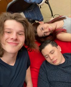 three people are laying down on the floor with their eyes closed and one person is looking at the camera