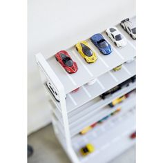 toy cars are lined up on top of each other in a storage unit with white shelves