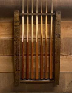 a rack with cues hanging from it's sides in front of a wooden wall