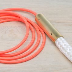 an orange and white rope with a gold handle on a wooden table next to a lighter