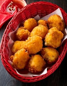 a red basket filled with fried food on top of a wooden table