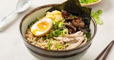 a bowl of ramen with an egg on top and chopsticks next to it