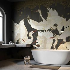 a bath tub sitting under a window next to a wall with birds painted on it